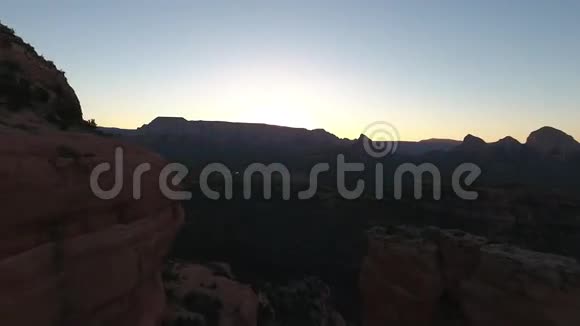 在温暖的傍晚日落中在大粉红色峡谷石岩悬崖的草原自然山景上观赏4k鸟瞰视频的预览图