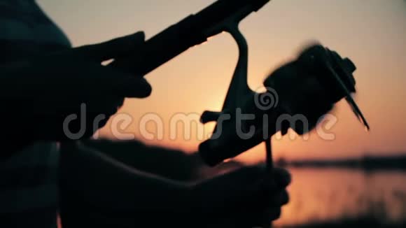 一个年轻女子的剪影手里拿着一根鱼竿在黎明时把钓索拉出来视频的预览图