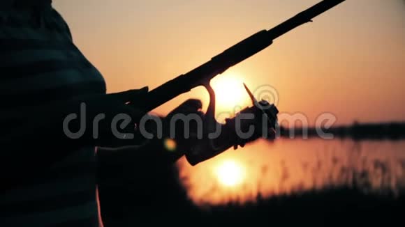 一个年轻女子的剪影手里拿着一根鱼竿在黎明时把钓索拉出来视频的预览图