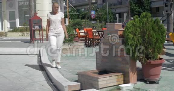 希腊比雷埃夫斯夏季街头公共喷泉中洗脸的年轻女子视频的预览图