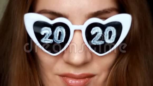 戴着太阳眼镜的女人号码是2020新年圣诞节女孩微笑着看着镜头选择性聚焦视频的预览图