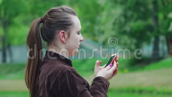 公园里的女孩在电话里写Facebook视频的预览图