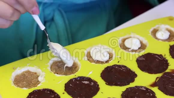 一个女人用压碎的杏仁覆盖融化的巧克力馅杏仁是有机硅形式的烹饪糖果白色和黑色的釉视频的预览图