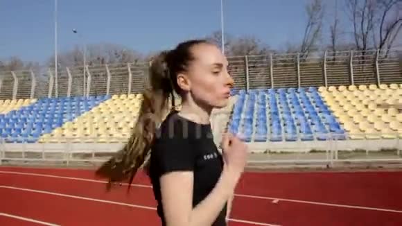 在阳光明媚的日子里近距离慢动作拍摄有魅力的年轻女子跑步慢跑户外体育场锻炼视频的预览图