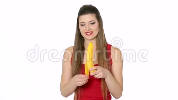 美丽的女孩在白色背景下吃香蕉视频的预览图