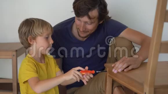 父亲和他的小儿子正在组装家具他们把厨房的椅子组装起来视频的预览图