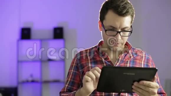 英俊的戴着眼镜的男人在一个有趣的视频上打电话在平板电脑上大笑视频的预览图