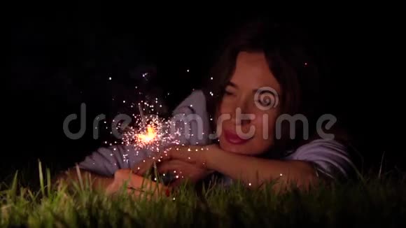 浪漫体贴的女孩躺在草地上晚上闪闪发光500fps超慢动作视频拍摄视频的预览图