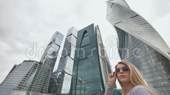 一个金发女孩欣赏市中心的摩天大楼和高层建筑慢镜头拍摄视频的预览图