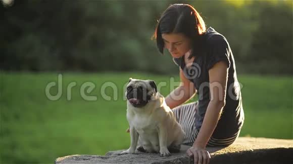 年轻漂亮的女人在公园里给她的狗吹吻可爱的警察亲吻一个女孩狗和主人坐在公园里视频的预览图