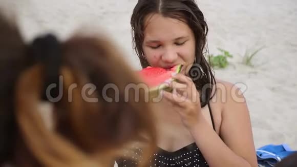 孩子们在海滩上吃西瓜女孩少年长着粉刺吃西瓜概念女孩和西瓜视频的预览图