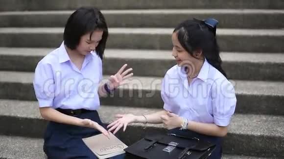 可爱的亚洲泰国高中女学生夫妇穿着校服和她的学生玩石头剪刀很开心视频的预览图