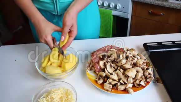 一个女人正在切土豆桌子旁边有切碎的蘑菇烤盘多汁的肉末和切碎的奶酪视频的预览图