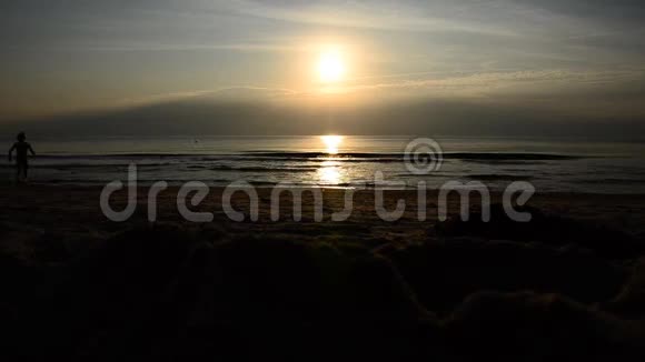 日落在海滩上玩的女孩视频的预览图
