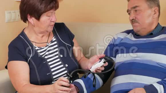 老年妇女在家里在沙发上测量血压穷人的幸福照顾他的妻子视频的预览图