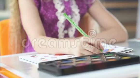 一支绿色铅笔在孩子手中的特写女孩用蜡笔画画视频的预览图