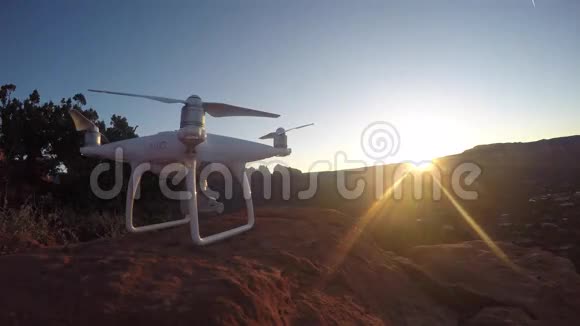 白色四翼飞机飞在峡谷草原石岩山景观傍晚日落4k空中视频的预览图