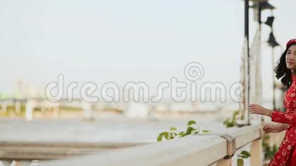 越南女孩穿着全国红裙傲黛在海边摆姿势微笑着为相机拍照视频的预览图