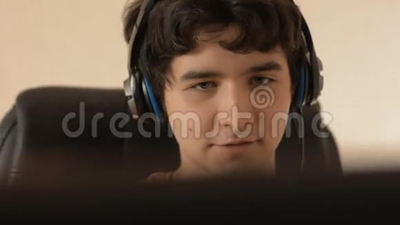 一位戴着耳机在电脑上工作的年轻人的特写镜头视频的预览图