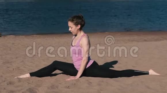 日落时分女人坐在沙滩上的树枝上伸展身体视频的预览图