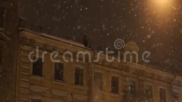 人从房子的屋顶降雪城市夜间大雪纷飞视频的预览图