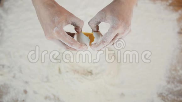 一位女面包店厨师用手把鸡蛋打碎成一堆面粉用一堆小麦做面包视频的预览图