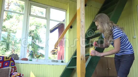 女农民女孩用画笔在花园的窗户前画木柱黄色4K视频的预览图