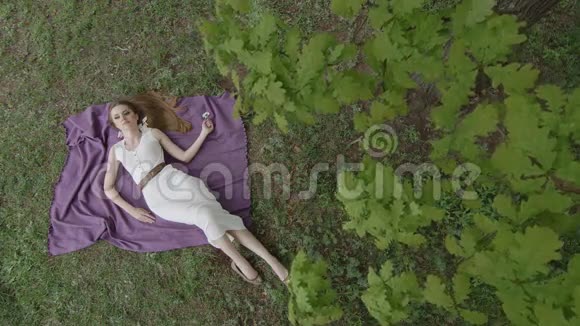 穿着白色裙子的漂亮女人躺在毯子上摆姿势视频的预览图
