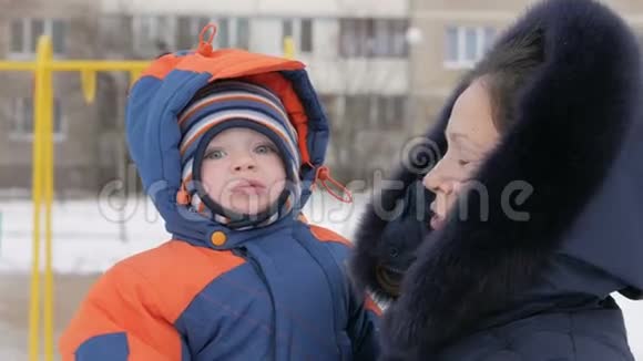 婴儿在他妈妈怀里冬天在公园里他们热情地穿着衣服母亲和她的儿子说话一个英俊的男孩视频的预览图