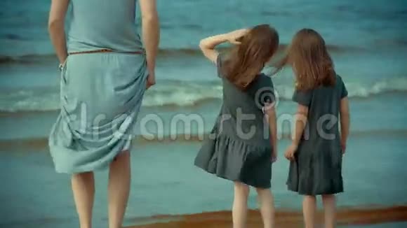 母亲和两个女儿站在沙滩上的水里视频的预览图