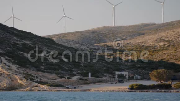 太阳下山时海洋海岸线上的风力发电机视频的预览图