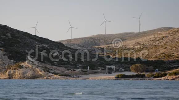 太阳下山时海洋海岸线上的风力发电机视频的预览图