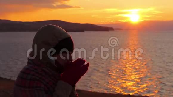 女孩坐在海边喝热茶美丽的金色夕阳视频的预览图