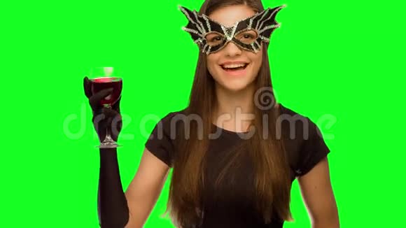 戴面具剧院的女孩和一件黑色连衣裙在Signet喝葡萄酒新年快乐并发送一个空气亲吻视频的预览图