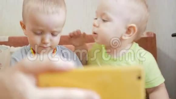 漂亮的兄弟孩子在电话上的视频链接上互相亲吻看着手机微笑着视频的预览图