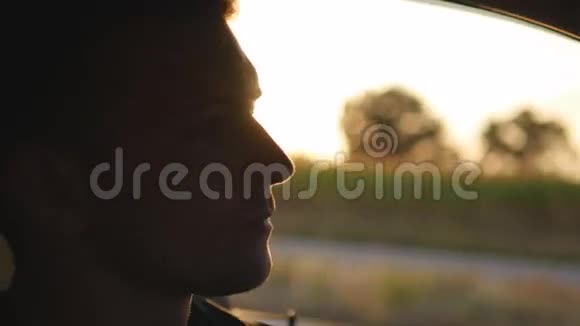 年轻英俊的男人在日落时开车在户外夕阳下开车的人孩子在里面视频的预览图