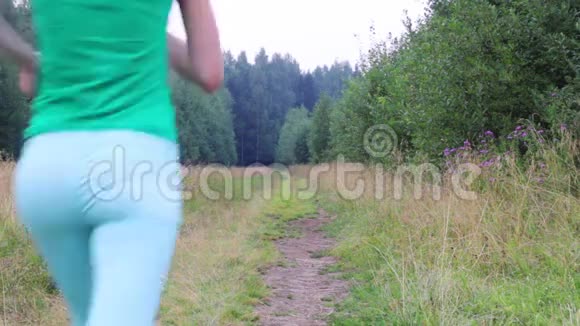 女孩在那里奔跑在夏夜回到森林附近的小路上视频的预览图
