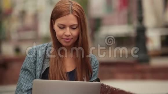 她用笔记本电脑在社交网络和街道上的微笑中交流视频的预览图