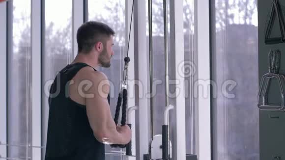 在运动中心锻炼身体的同时肌肉男在牵引模拟器上进行肌肉锻炼视频的预览图