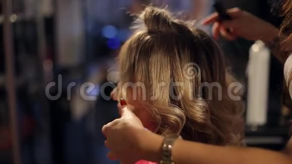 美容美发店里的理发师给金发女孩做发型视频的预览图