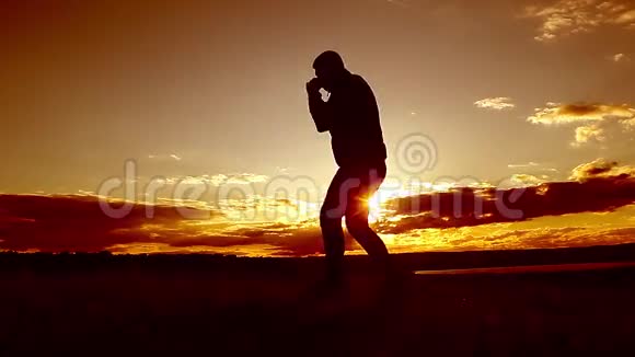 男子拳击剪影与阴影在日落时有意太阳耀斑和复古的颜色从事近战战斗的人视频的预览图