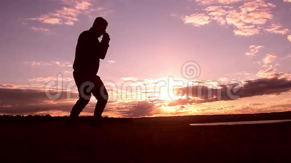 男子拳击剪影与阴影在日落时有意太阳耀斑和复古的颜色从事近战战斗的人视频的预览图