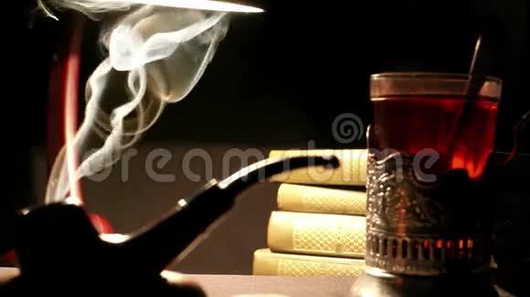 烟斗放在桌子上旁边放着一杯茶和一叠书视频的预览图