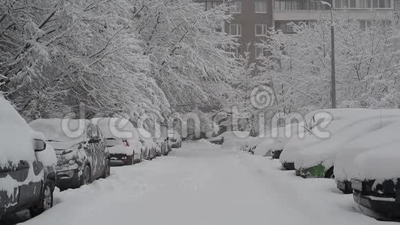 房子附近的人行道上有一排积雪覆盖的汽车莫斯科俄罗斯视频的预览图