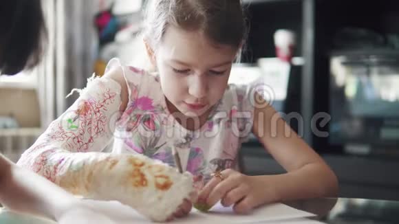 带着绷带的断臂的孩子用彩色铅笔画画有抹灰手的女孩视频的预览图