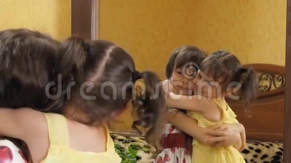镜子前的孩子们姐妹们在拥抱镜子前的小女孩视频的预览图