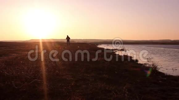 运动积极的人在日落时在海滩上跑步和锻炼的剪影视频的预览图