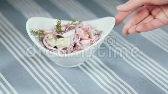一只雌性的手转动一个白色的盘子桌子上放着沙拉背景是一块蓝色桌布视频的预览图
