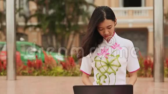 穿着国服坐在公园里拿着笔记本电脑的漂亮亚洲女孩视频的预览图