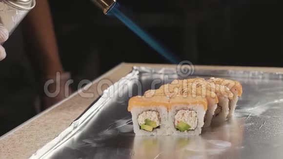 专业寿司厨师在商业厨房通过火准备卷特写视频的预览图
